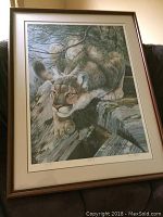 Framed full view of the print showing a crouching cougar in a natural setting, framed with matte and wooden frame.