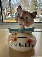 Front view showing cat face, turquoise bow, coin slot and text