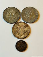 Reverse sides of three large silver-tone coins and one small brown cent