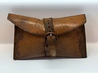 Front view of cracked brown leather pouch with strap buckle
