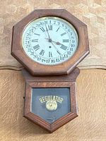 Full view of octagonal oak regulator wall clock on wall