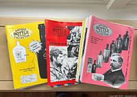 Front covers of several Antique Bottle & Glass Collector magazines in two stacks