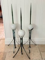 three copper lightning rods with glass globes and tripod bases