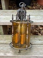 Full view of brass lantern showing amber glass and hanging loop