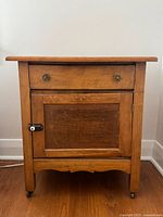 Front view of oak washstand showing drawer, door, hardware and casters