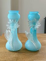Front view of both blue satin glass vases showing applied daisy and leaf