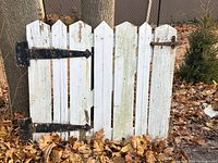 Front view of white wooden picket gate showing hinges and latch