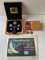 Group view: 1980 wood boxed set, loose 1978 half dollars, sealed 1995 Peacekeeping set