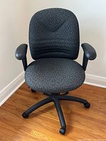 Front view of dark grey ergonomic office chair showing seat, backrest, armrests, base with casters