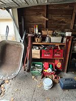 Overall view showing metal wheelbarrow, shelving with crates and bins of garden items