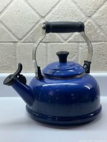 Front view of blue Le Creuset whistling kettle showing body, handle, spout lever