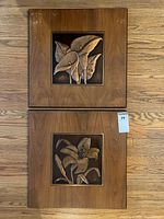 Two framed embossed copper floral plaques displayed vertically