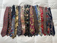 Front view of 22 assorted men's neckties laid out side by side showcasing patterns and colours