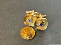 Front view of cufflinks and penny showing Masonic emblems