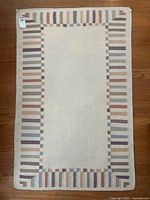 Full view of rectangular cream rug with striped pastel border