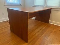 Angled front-left view of full teak desk showing side panel and modesty panel