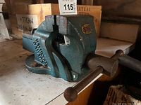 Side view of blue-green cast iron bench vise showing jaws, screw handle, swivel base and maker decal