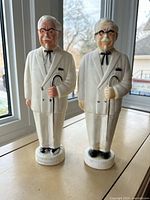 Front view of both Colonel Sanders coin banks