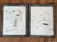 Both framed lithographs side by side on floor