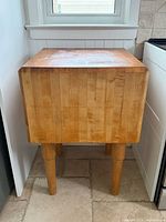 Front view of square maple butcher block on four legs