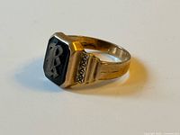 Oblique view of gold signet ring showing black inlay and engraving