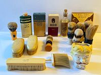 Group shot of entire lot: talc tins, brushes, ceramic mug, mirror sleeve, lotion bottle and hair brushes