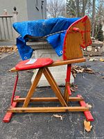 Full side view of pine wood rocking horse with red painted saddle and trim