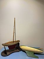 Both pond boats: Star Yacht on stand with mast, second green-bottom hull beside it