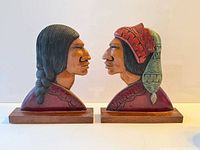 Front view of both painted wooden bust carvings on bases