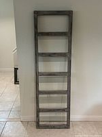 Full view of grey painted six-rung wood ladder leaning against wall