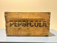 Front view of wooden crate showing Pepsi-Cola logo and overall wear