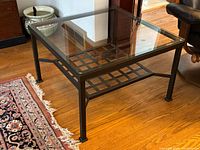 Full view of square wrought iron coffee table with glass top on hardwood floor