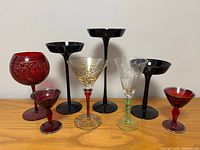 Group shot of three black candle holders and five coloured drinking glasses