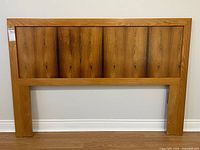 Front view of rectangular wooden headboard against wall