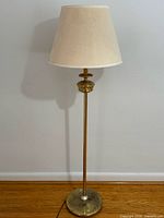 Full view of brass floor lamp with cream shade