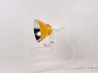 Side view of yellow metal cone spotlight with white clamp and cord