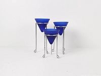 Three cobalt blue glass votives on chrome stands grouped