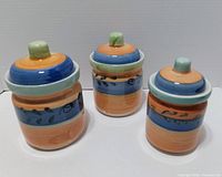 Front view of three graduated ceramic canisters with lids in place