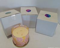 Three white boxes and one unboxed Aeropostale 3-wick candle