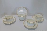 Group view of four cups on saucers with one saucer displayed upright showing pattern