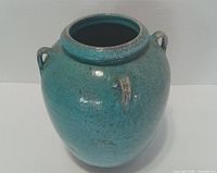Front angle of turquoise ceramic wine jug showing glaze and handles