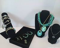 Overview of necklaces, bracelets, and earrings displayed on black stands and tray