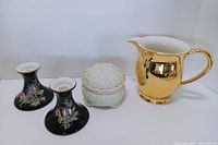 Full group shot of two candlesticks, trinket box with lid, and gold pitcher