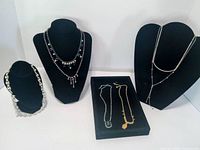 Group shot showing all seven rhinestone necklaces on display busts and tray