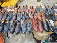 Wide shot of table filled with assorted men’s dress shoes in multiple colours and styles