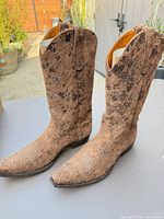 Three-quarter front view of the pair of brown hair-on-hide cowboy boots on tabletop