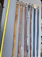 Ten belts laid out beside tape measure