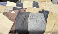 Assorted men’s dress pants laid out showing variety of colours and styles