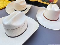 Three natural straw cowboy hats on table