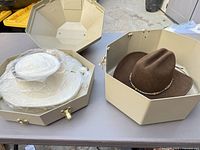 Two hats each inside beige octagonal hat boxes; shows overall lot contents